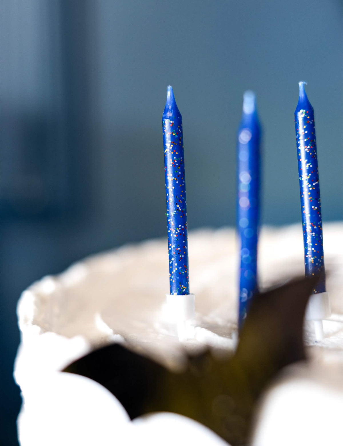 Zoom sur le support et les paillettes des 12 bougies d'anniversaire pour gâteau bleues pailletées
