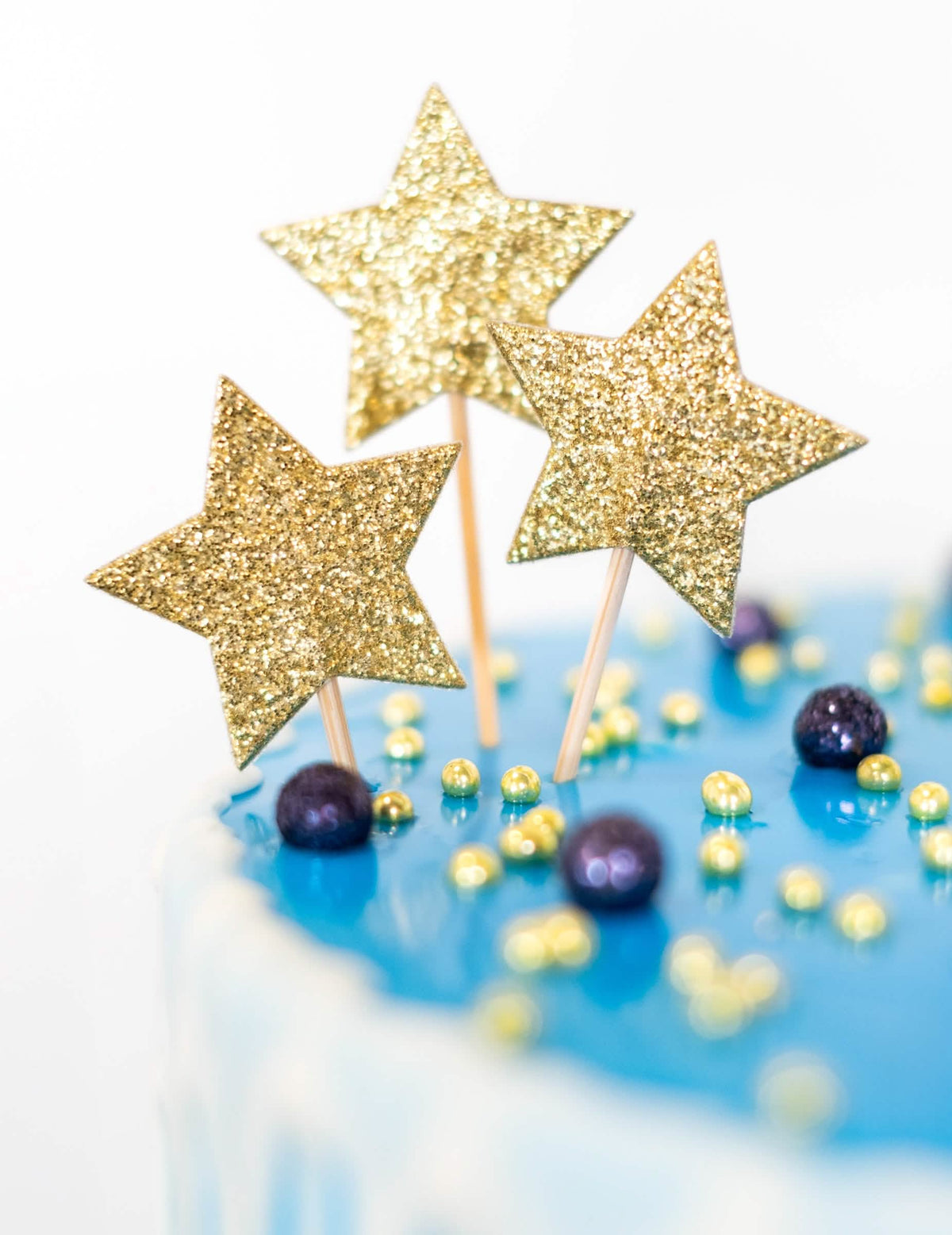 Primer plano de las purpurinas doradas del cake topper sobre pincho estrella para cumpleaños
