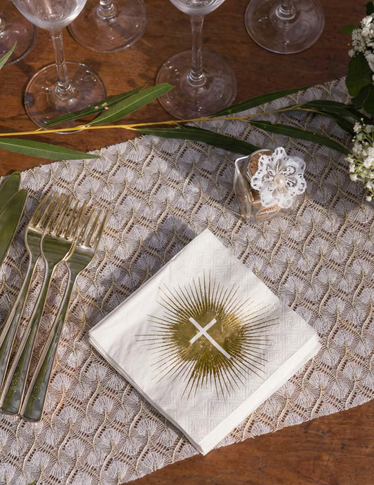 Mise en situation sur une table des serviettes papier cérémonie croix blanche et dorée
