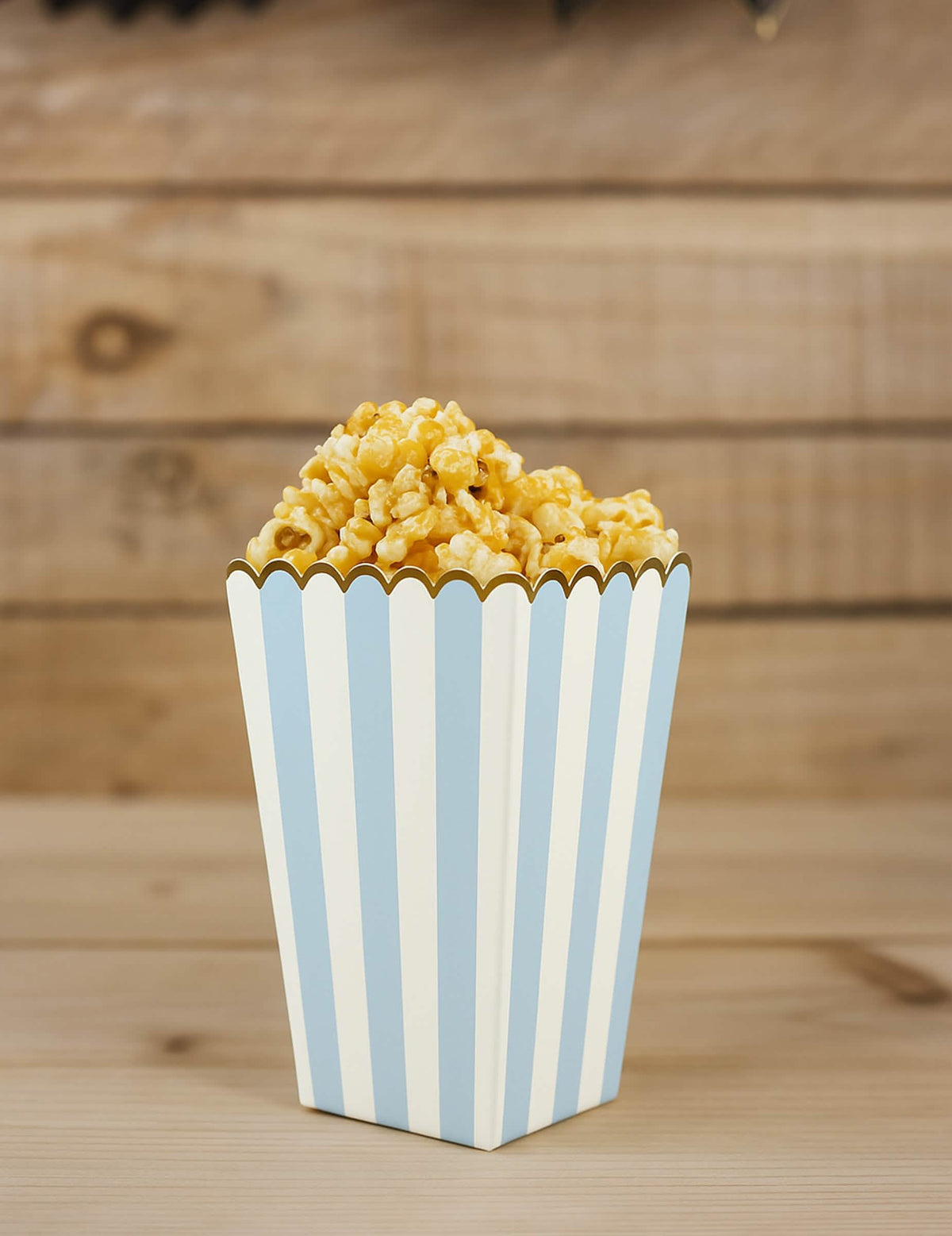 Vue d'une boîte remplie des boîtes à pop corn pour fête bleu pastel et or en carton rayé