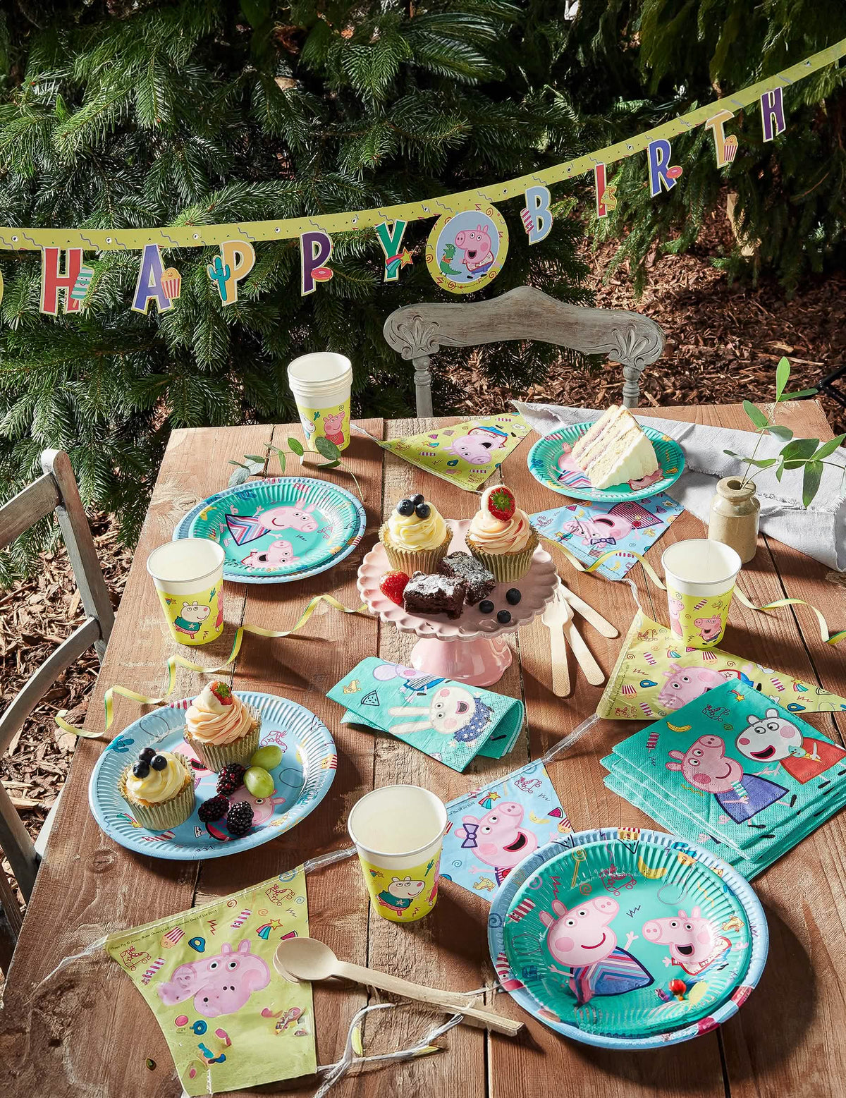 Vista general de la mesa de fiesta con guirnalda de vasos de cartón Peppa Pig