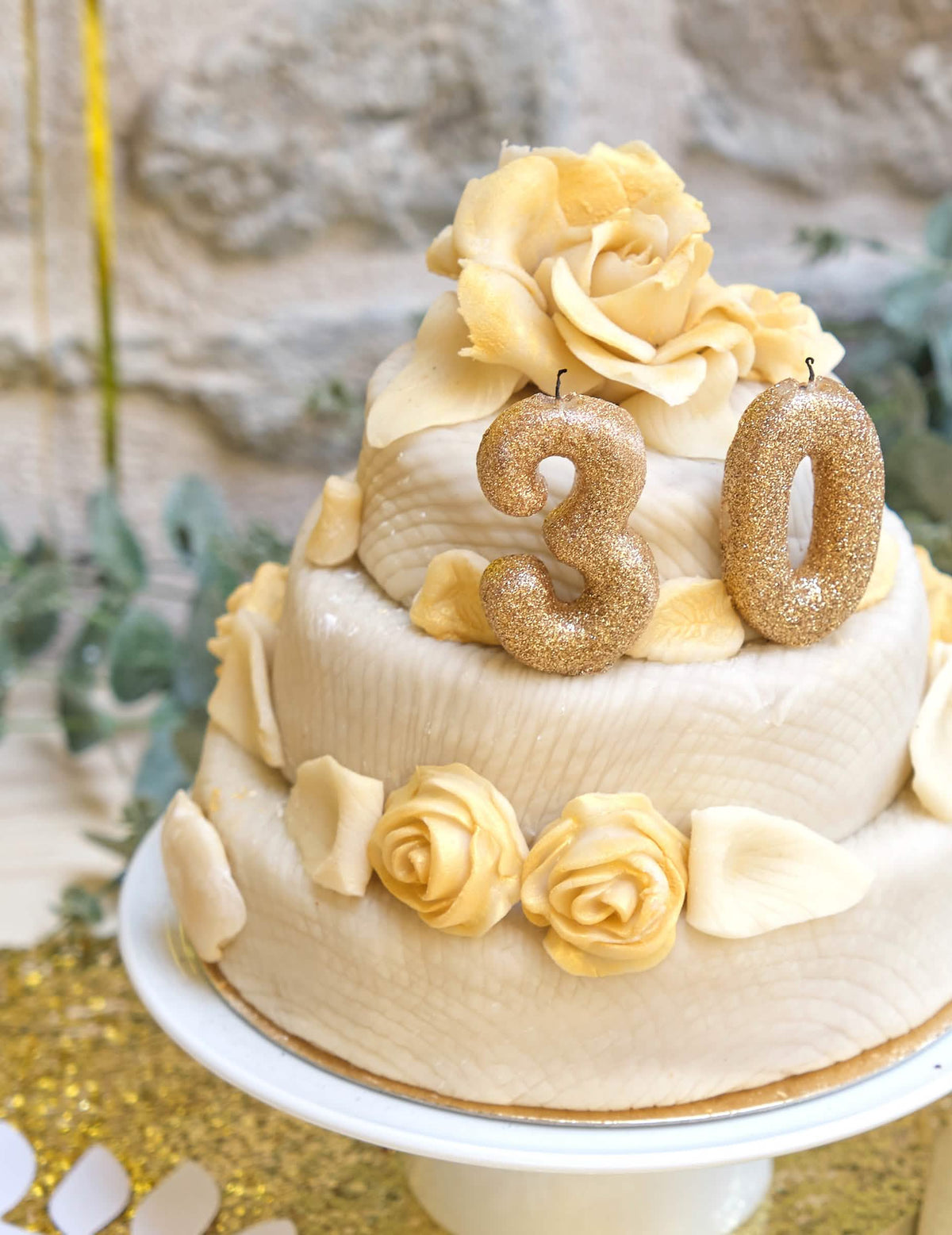 Primer plano de un pastel con una vela de número 0 para cumpleaños dorado con purpurina