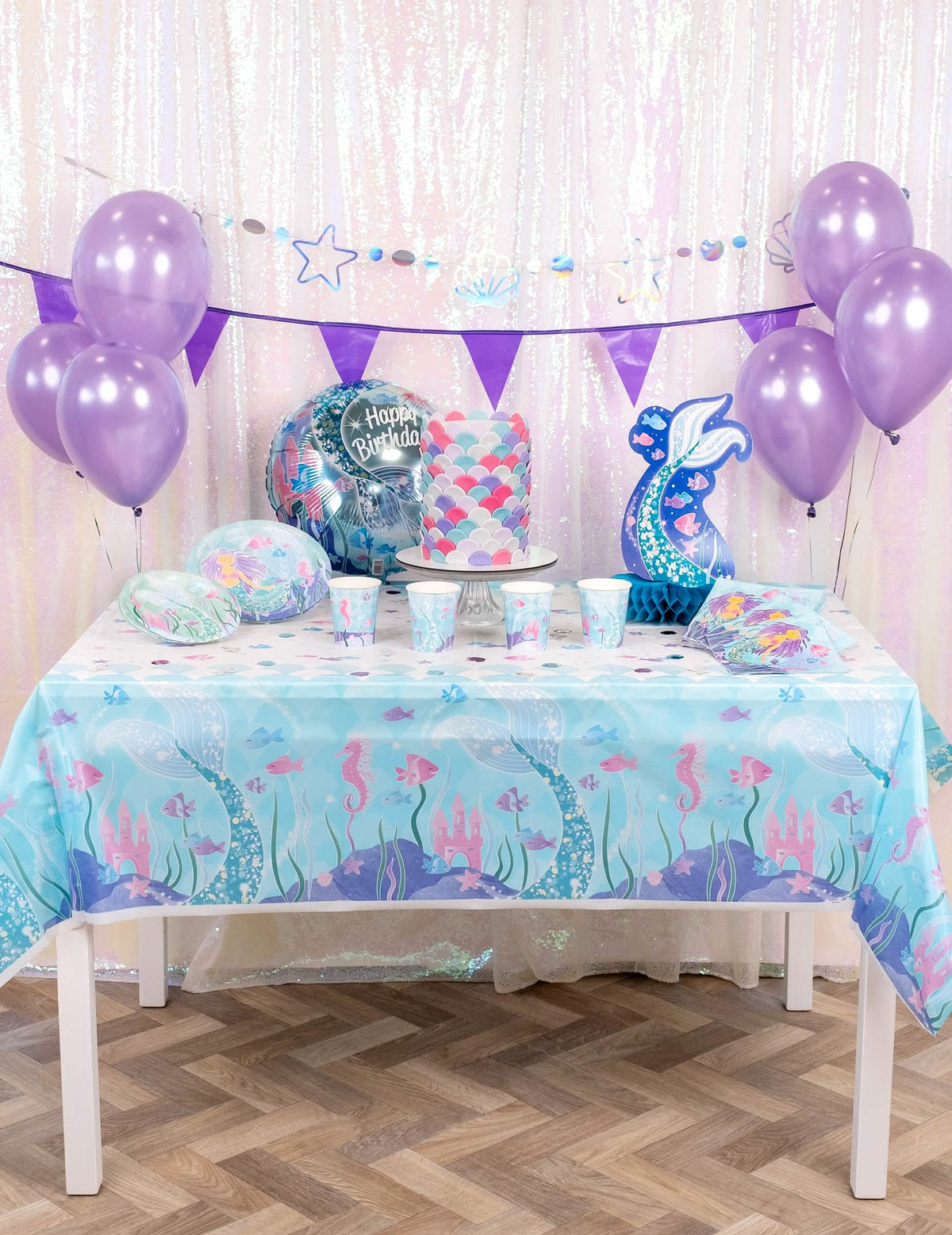 Vista general de la mesa de fiesta con el bonito mantel de plástico de sirenas