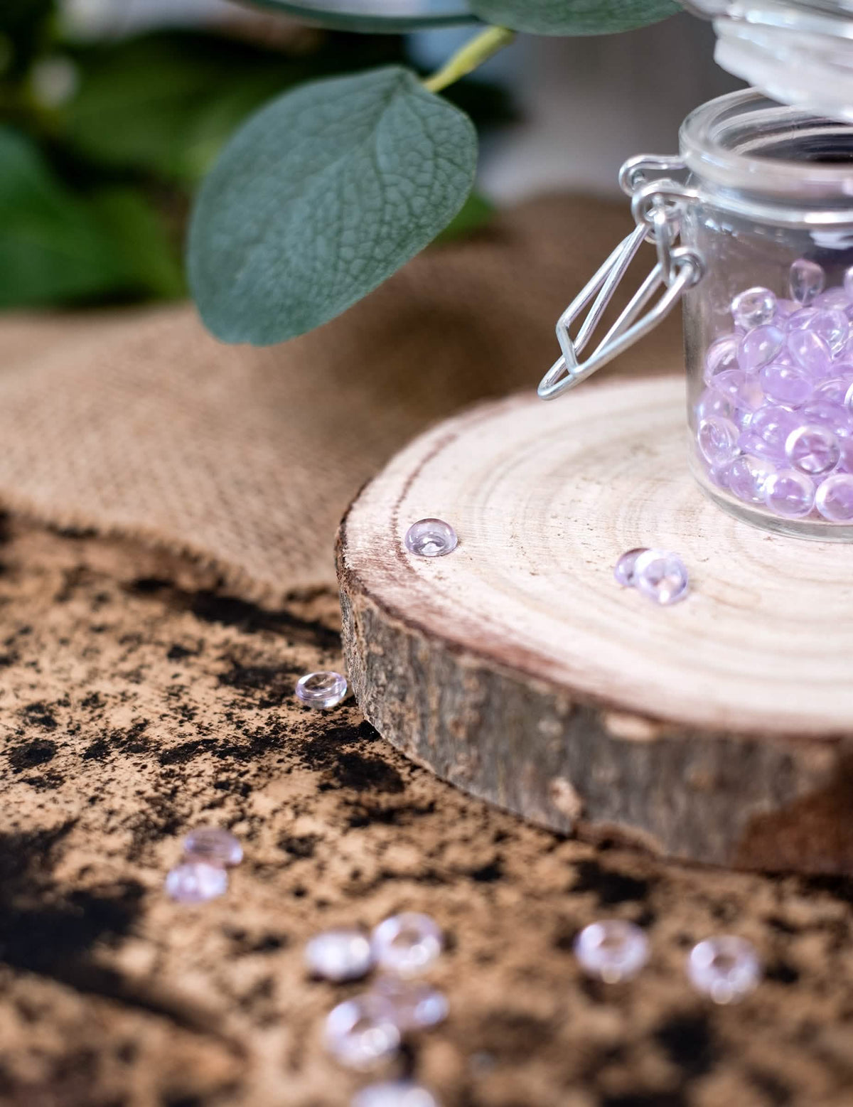 Détail des perles éparpillées sur le rondin de bois des perles effet goutte de pluie pour décoration de table parme