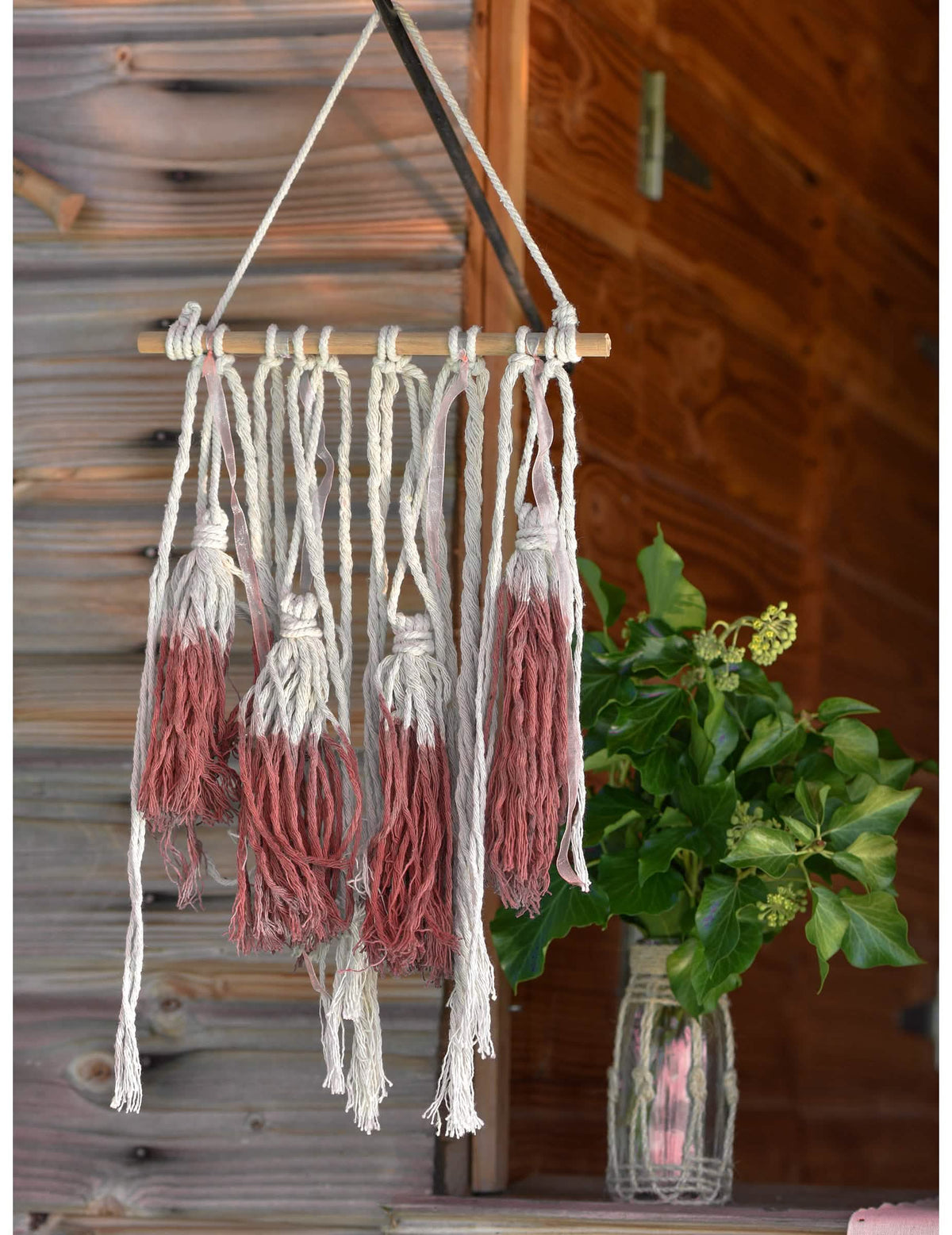 Vista general de la suspensión de madera macramé para decoración con pompones rojos