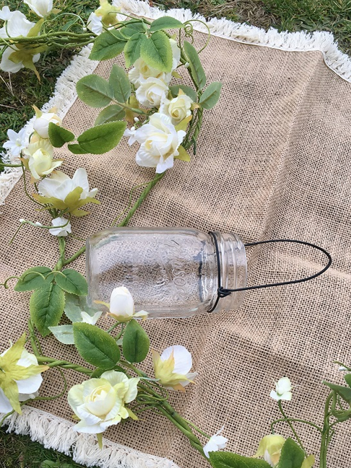 Puesta en escena sobre tela de arpillera del jarrón de vidrio mason jar