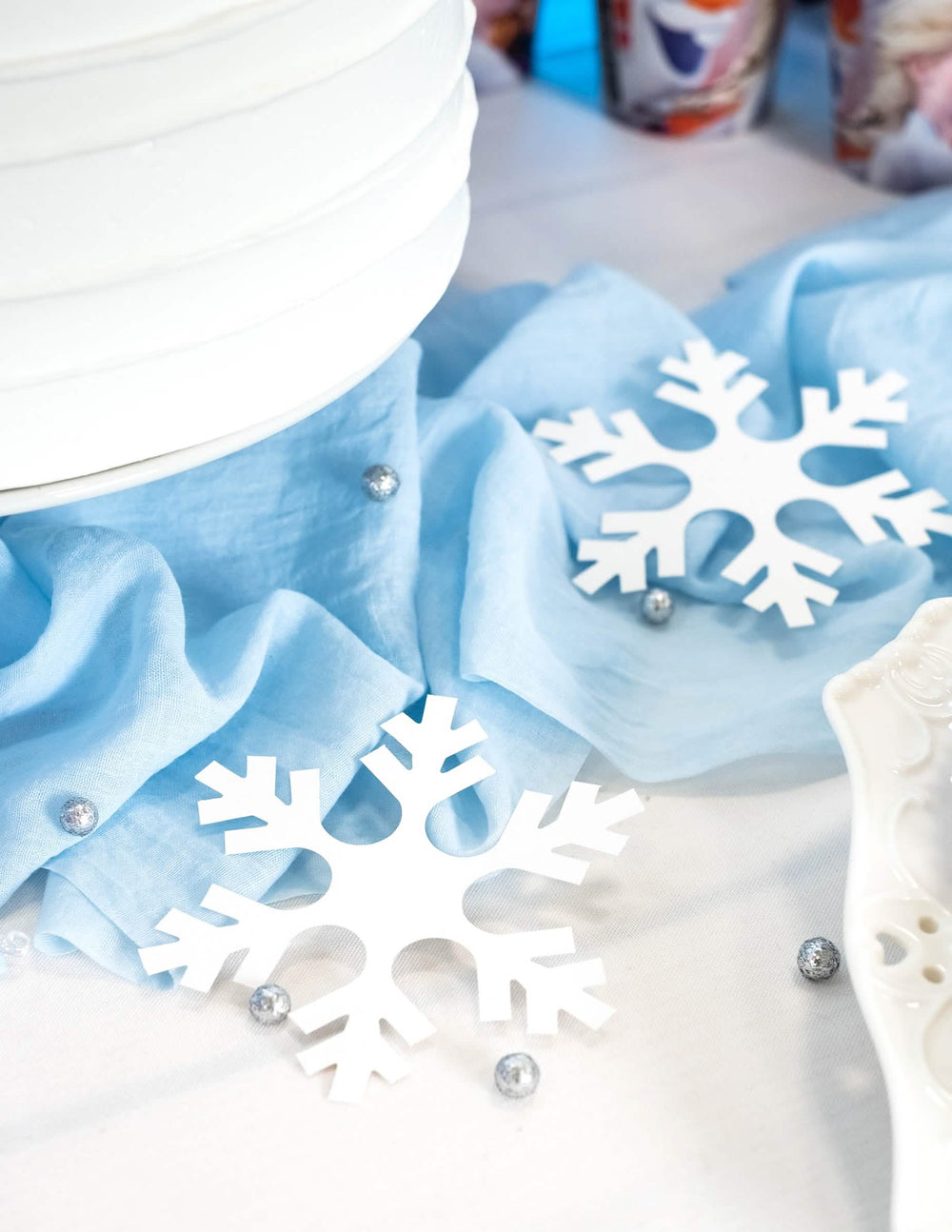 Ambientación sobre camino de mesa azul con copos de nieve de navidad para decoración