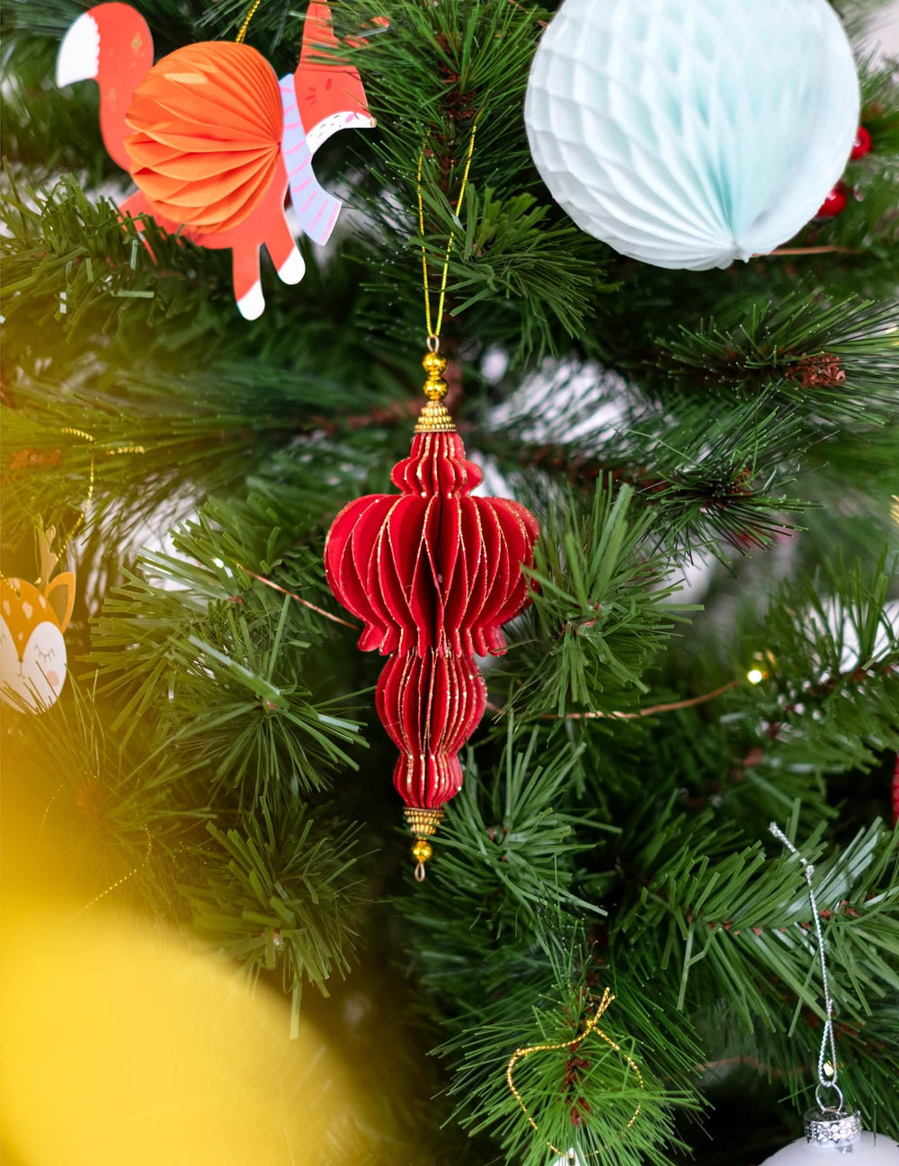 Colocación en un árbol de suspensiones origami rojas y doradas para fiesta