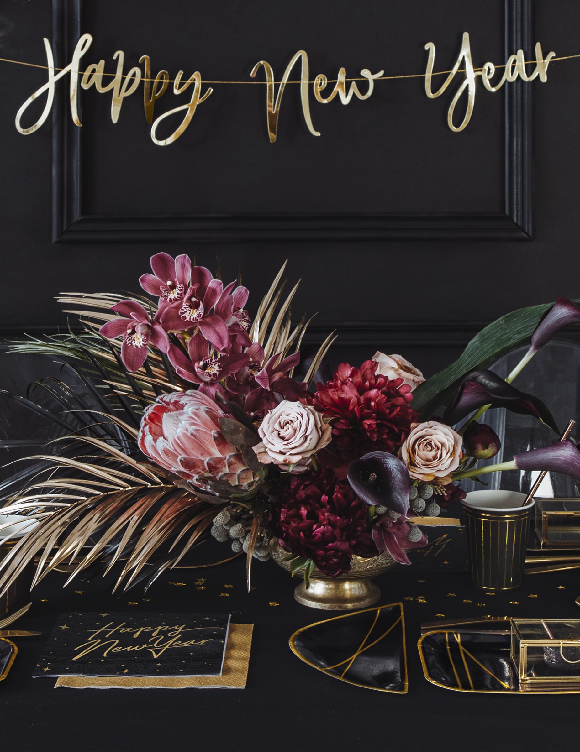 Mise en situation sur une table de fête des serviettes en papier Happy New Year noires et dorées avec décor étoilé