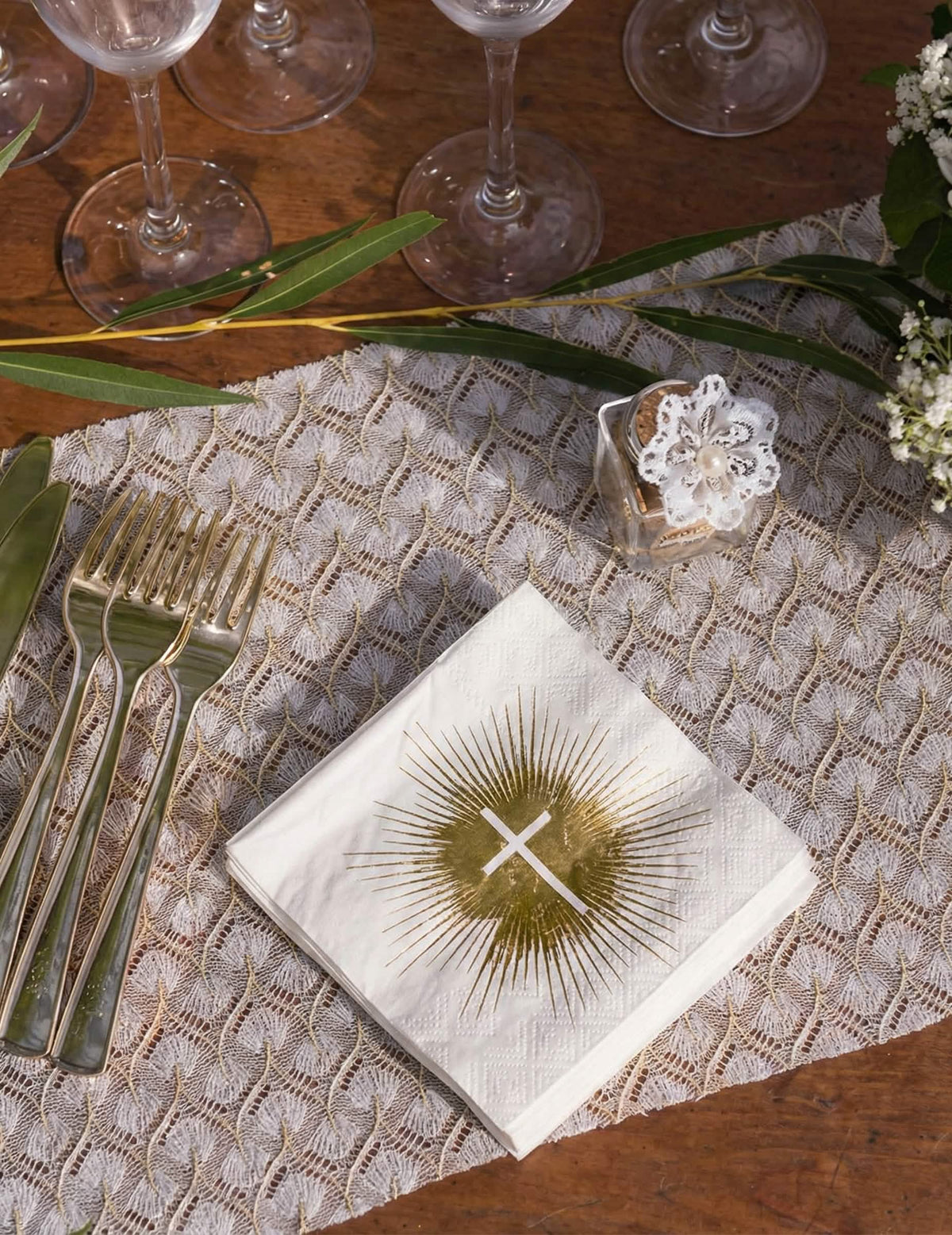 Mise en situation sur une table des serviettes papier cérémonie croix blanche et dorée