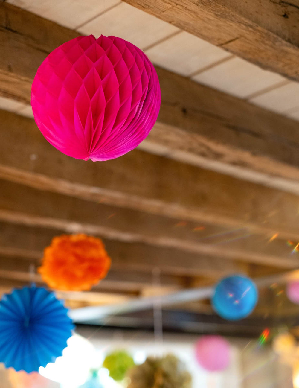 Mise en situation au plafond des boules en papier alvéolé à suspendre pour décoration rose fuchsia