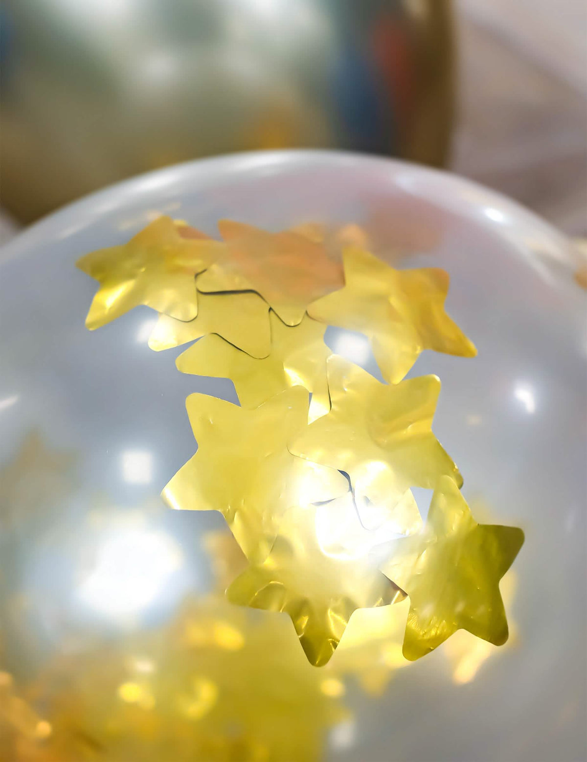 Detalle de los confetis de estrellas del globo de látex transparente con estrellas doradas