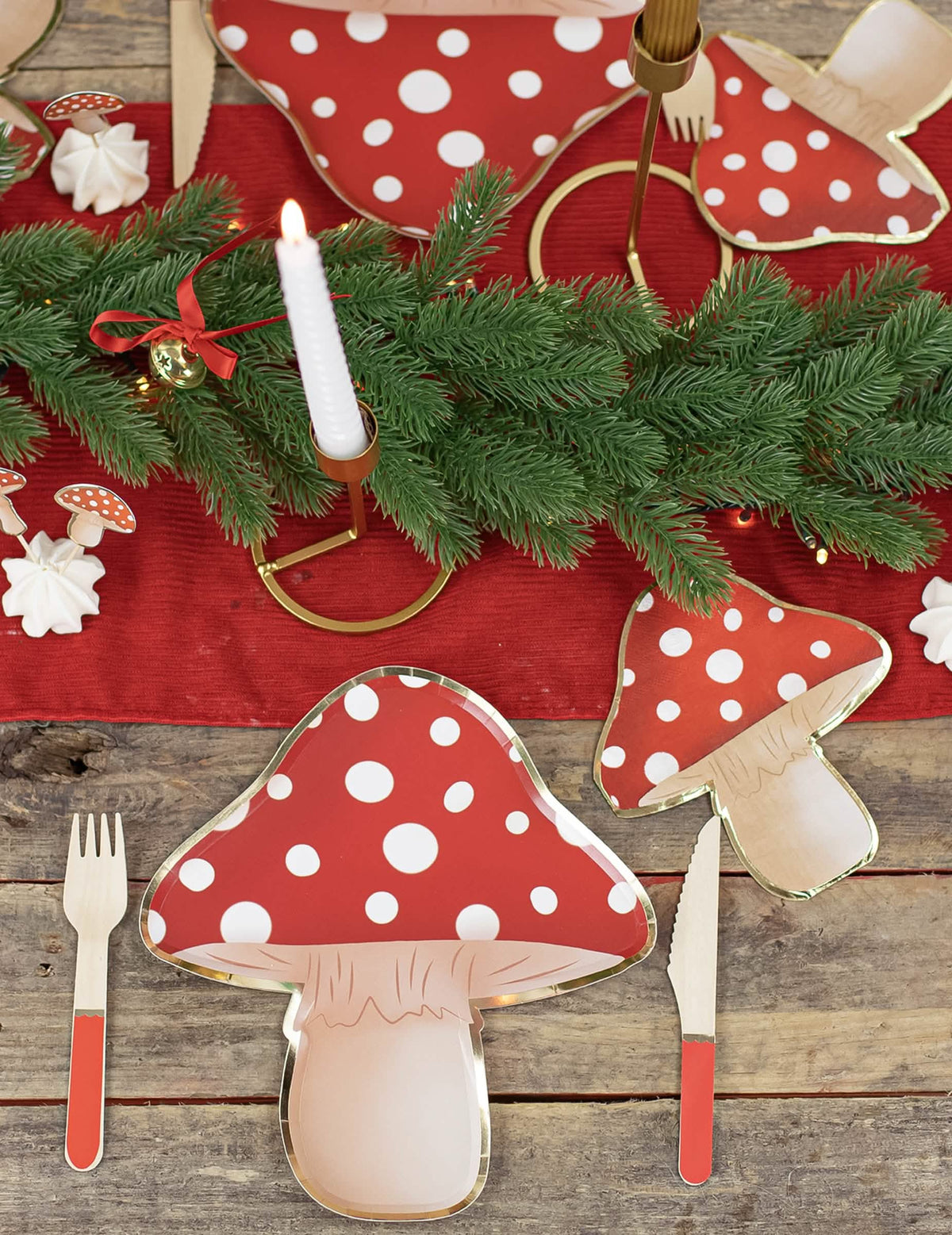 Mise en ambiance avec guirlande de sapin et bougie des assiettes en carton champignon rouge et blanc à pois