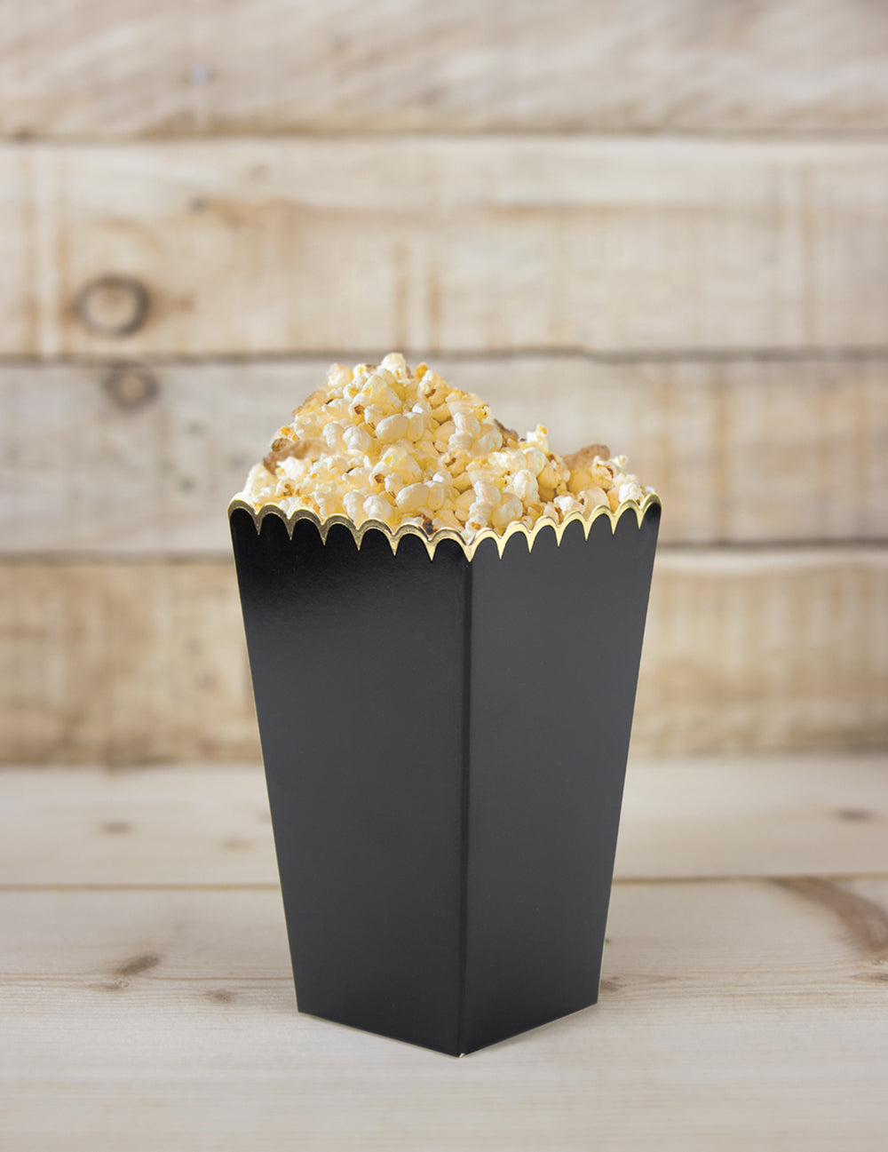 Gros plan d'une boîte remplie des boîtes à pop-corn festonnées pour fête noires et or