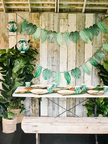 Escena sobre una mesa de vasos de cartón tropicales verde con motivos de hojas de palmera