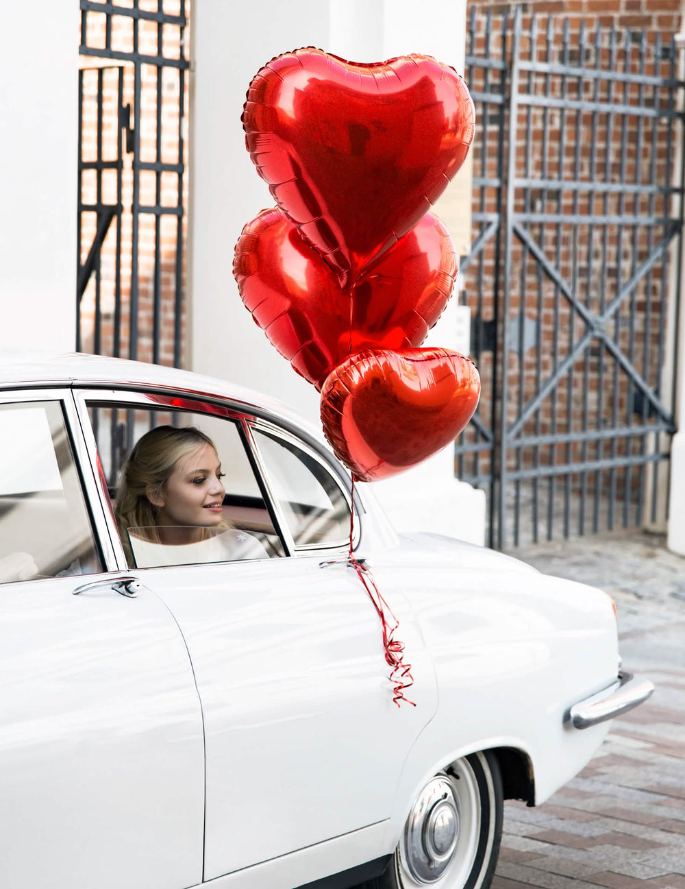 Mise en situation sur une voiture du ballon aluminium coeur pour fête rouge métallisé