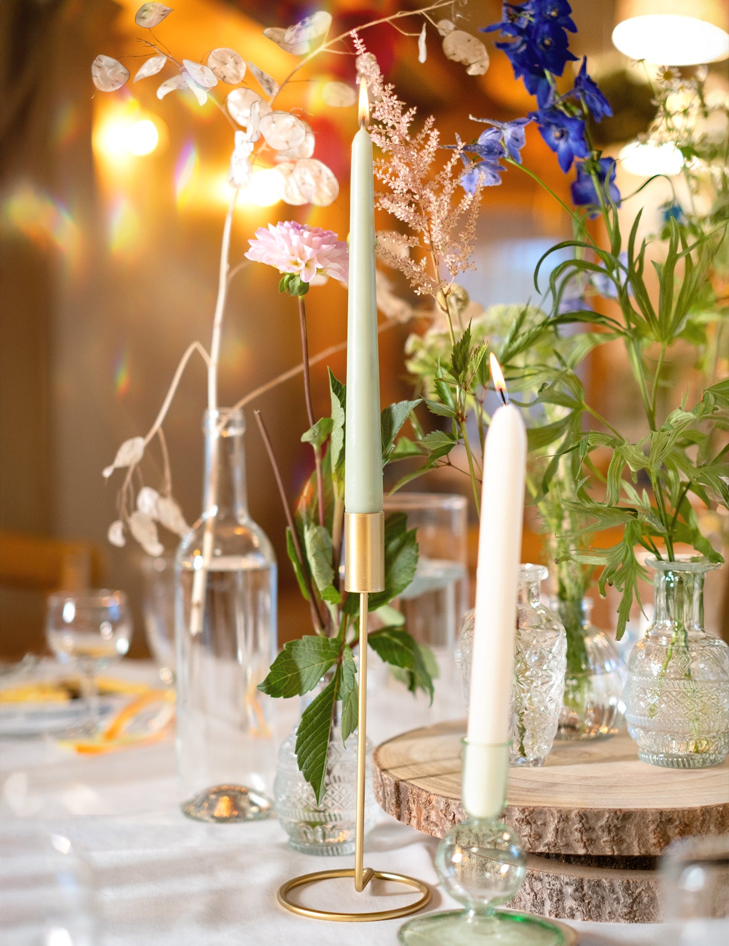 Mise en situation dans un décor floral du bougeoir design sur pied pour table métal doré