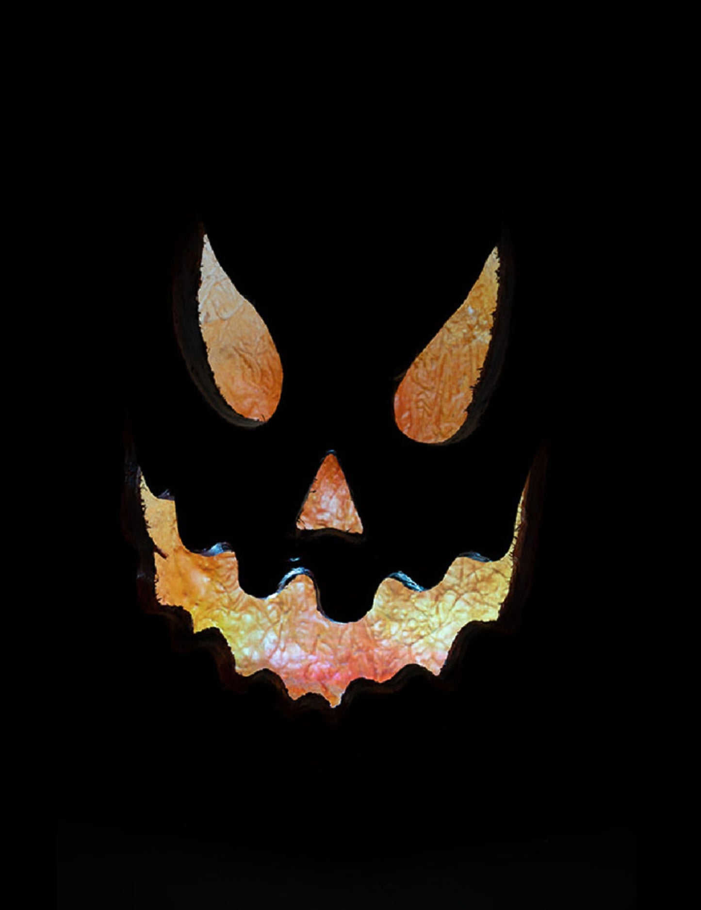 Gros plan sur le regard et la bouche découpés de la citrouille lumineuse effrayante pour Halloween