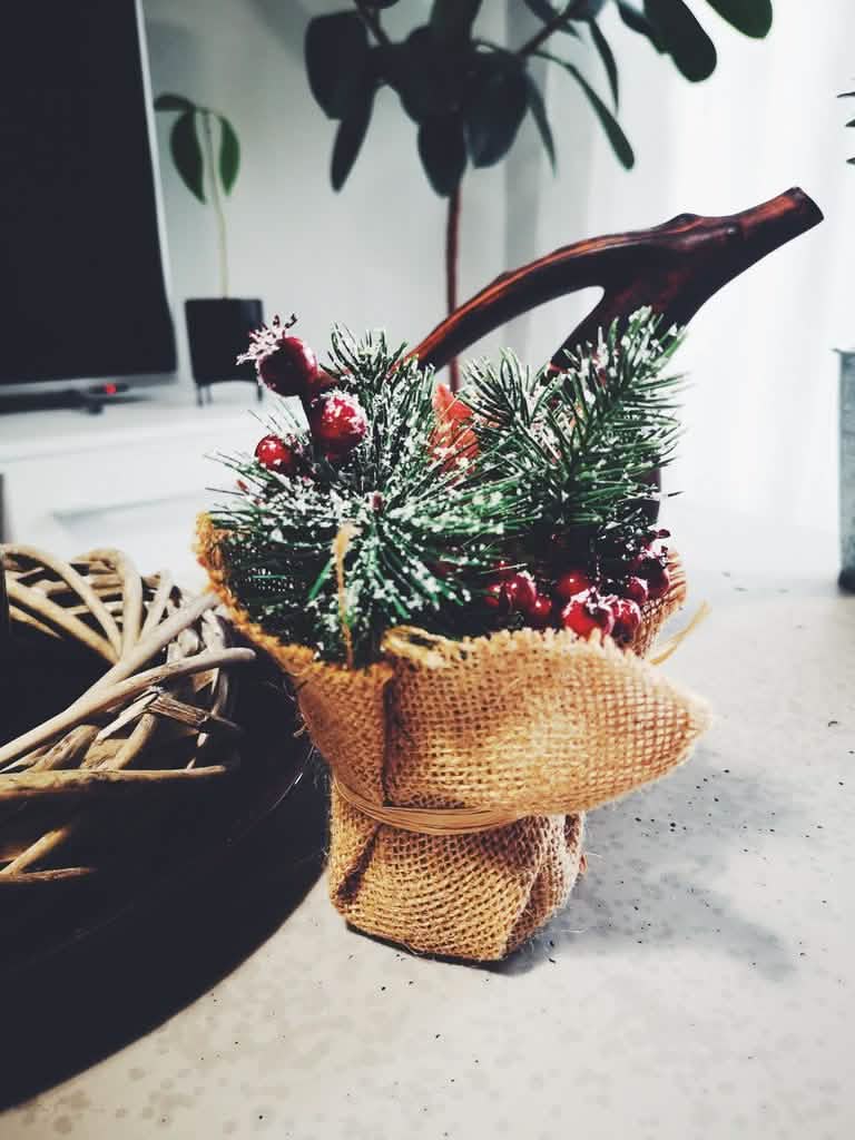Detalle de la maceta de yute de la composición de navidad con bayas rojas y abetos nevados