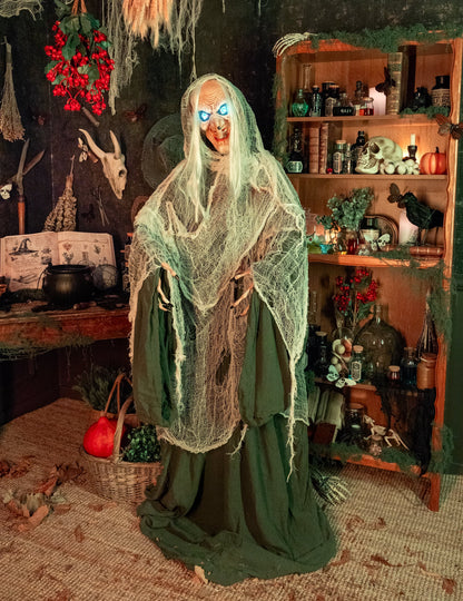 Mise en situation dans un décor d'Halloween de la décoration animée sonore et lumineuse Sorcière Andromeda