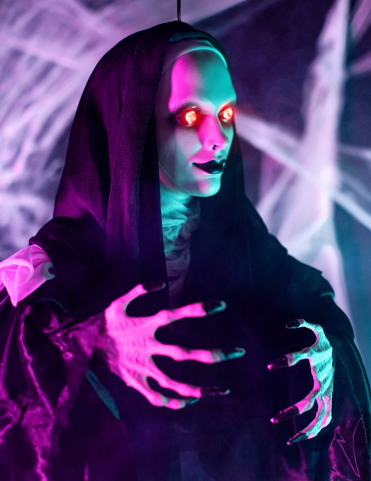 Gros plan sur le visage aux yeux rouges et les mains de la décoration lumineuse nonne suspendue