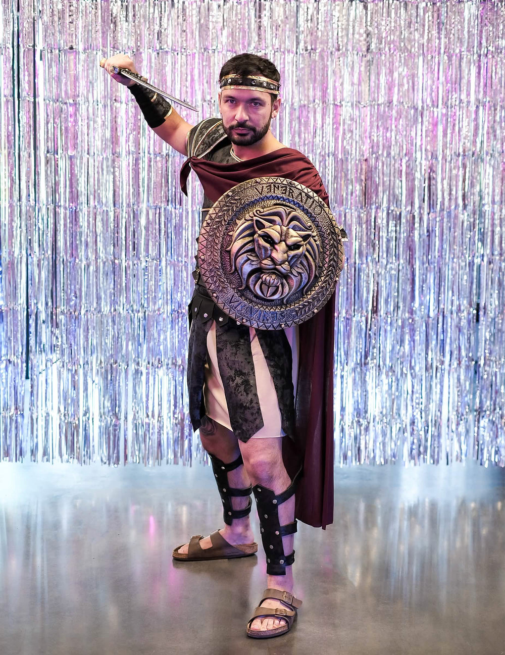 Mise en situation avec bouclier à tête de lion et épée du déguisement de gladiateur romain pour homme