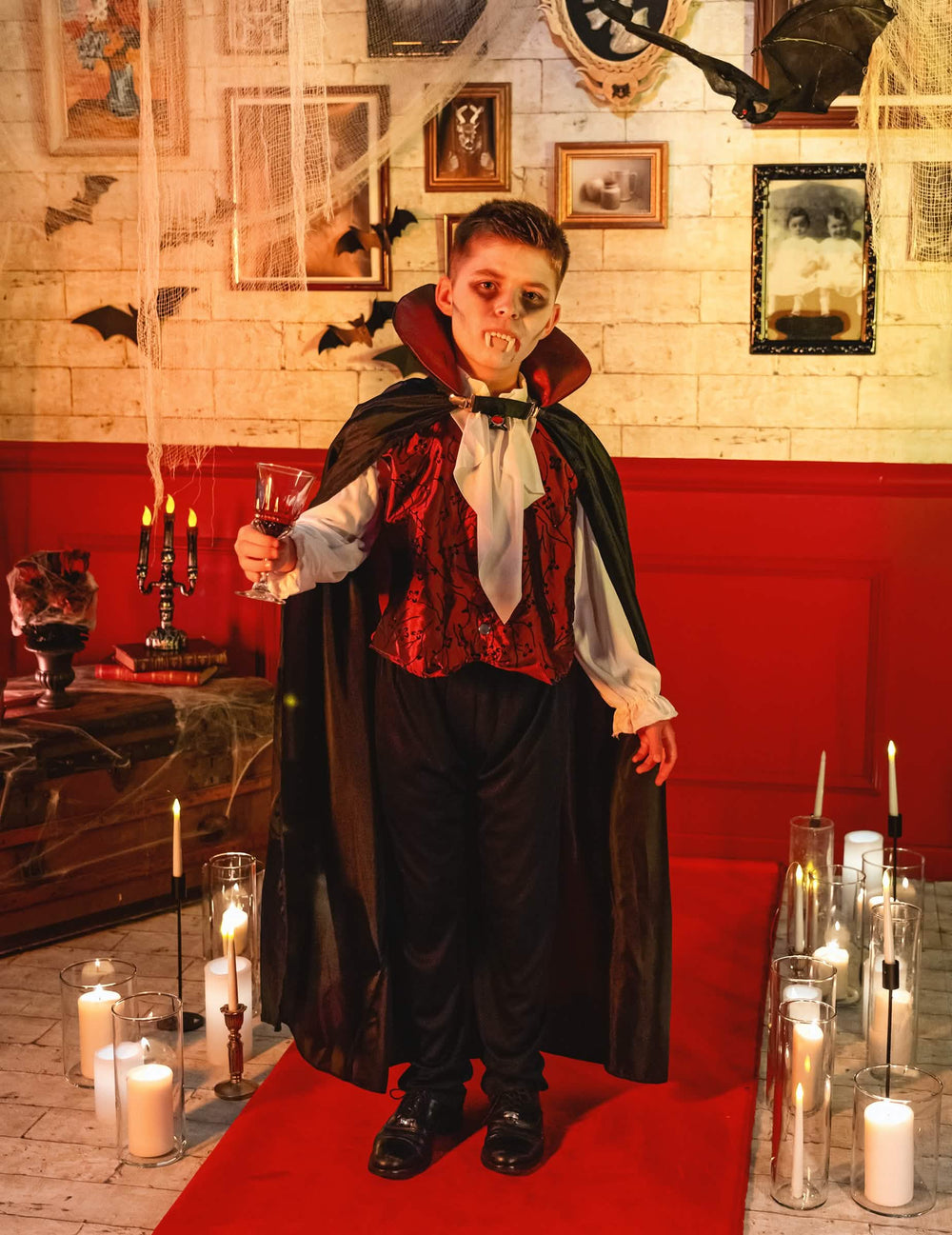 Escenificación del disfraz de vampiro elegante para niño en un decorado de halloween con velas