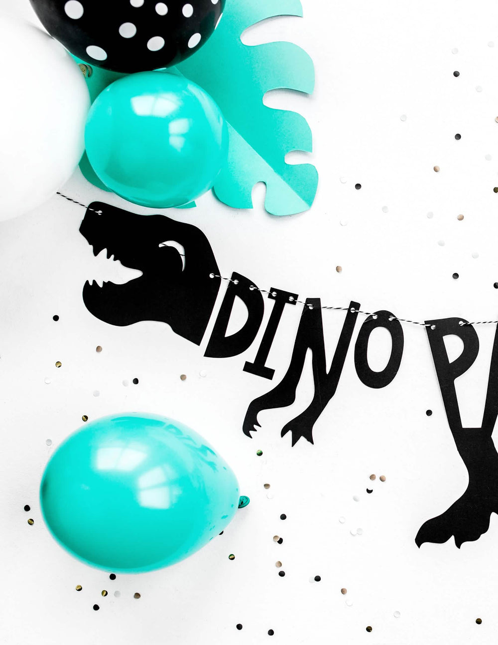Mise en situation avec ballons et confettis de la guirlande en carton squelette dino party