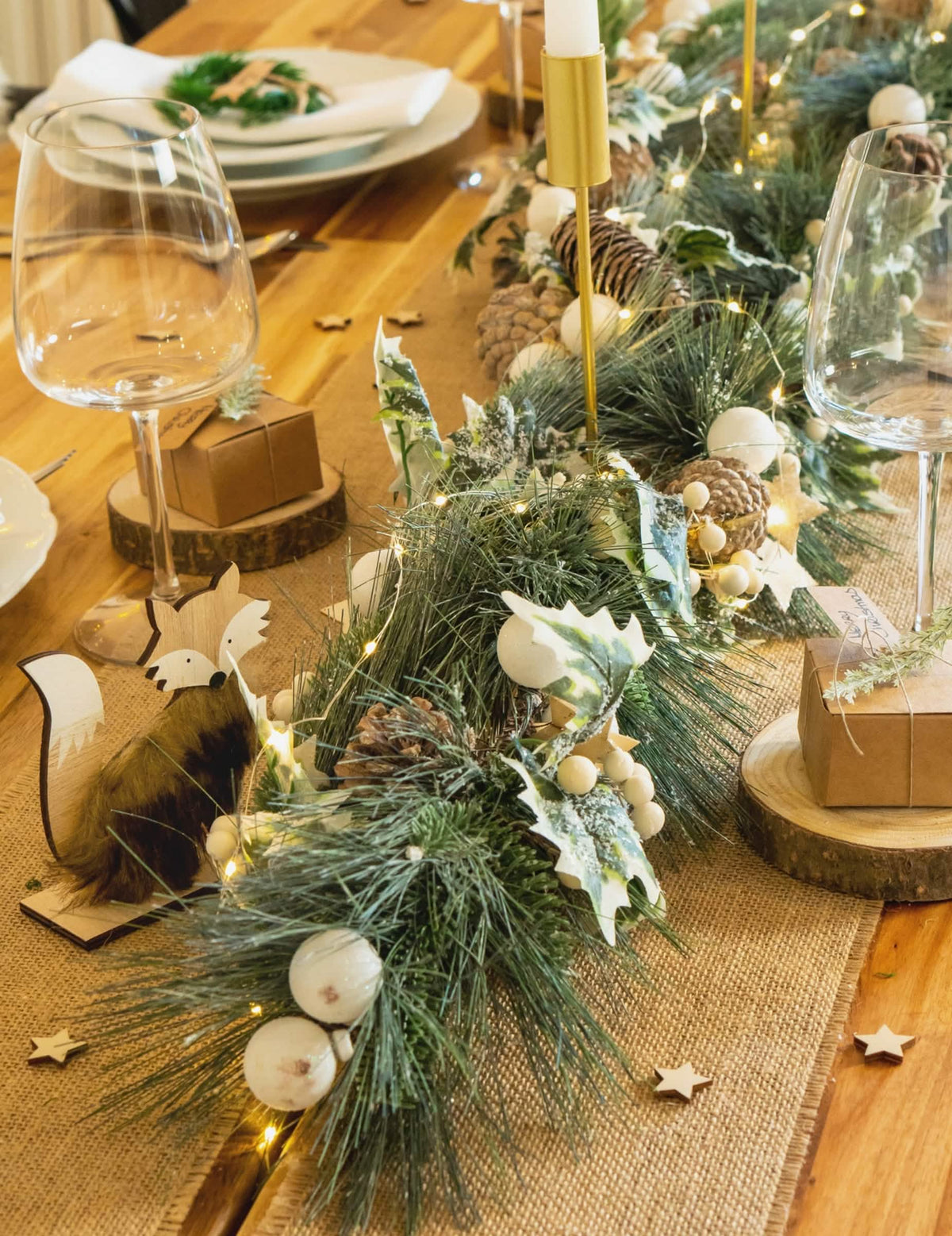 Mise en scène sur table de la guirlande de Noël feuillage vert et pommes de pin