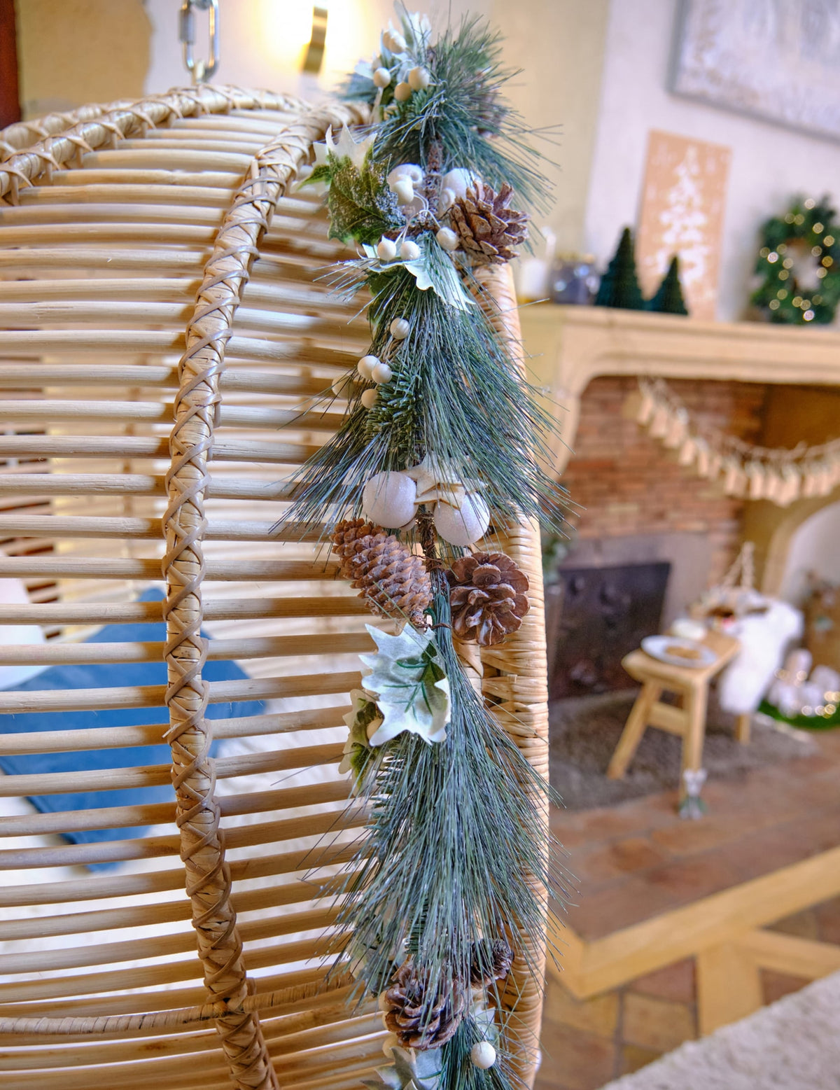 Mise en situation sur un fauteuil de la guirlande de Noël feuillage vert et pommes de pin