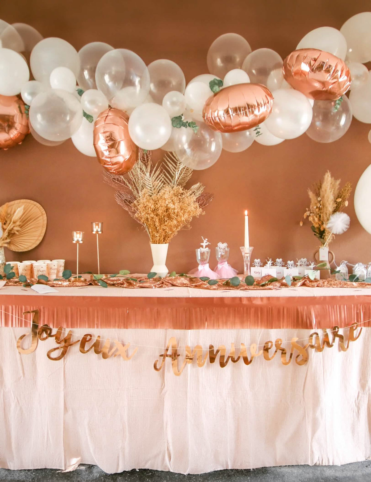 Mise en situation sur une table de fête de la guirlande Joyeux Anniversaire pour fête rose gold