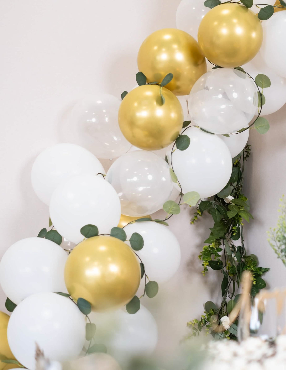 Primer plano de la decoración vegetal del kit de arco de 60 globos blancos y dorado con eucalipto vegetal