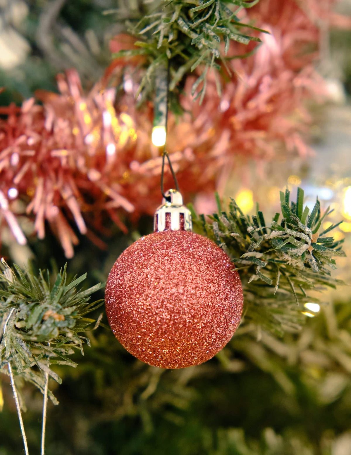 Primer plano de una bola brillante del kit de decoraciones para árbol oro rosa