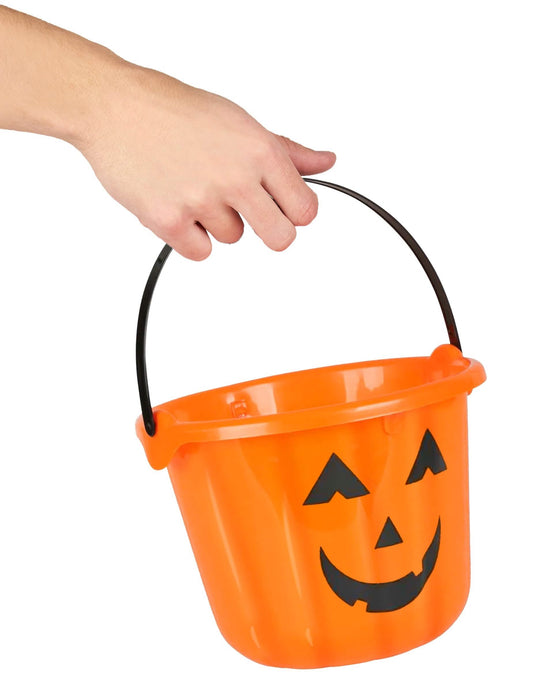 Detalle del asa sostenida por una mano del cubo calabazas para halloween