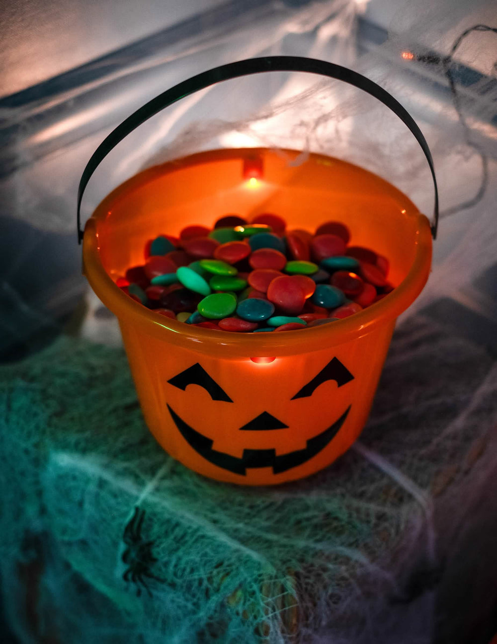 Primer plano de los caramelos dentro del cubo de calabazas de halloween