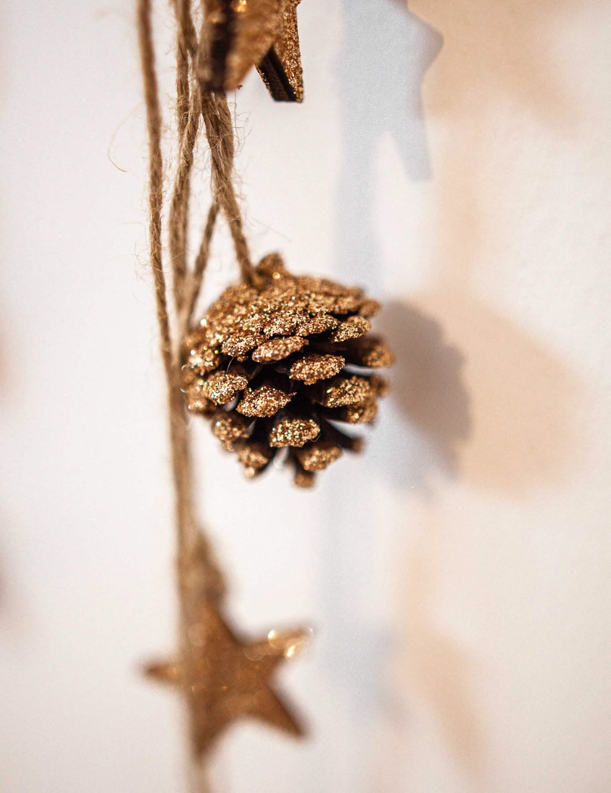 Gros plan sur la pomme de pin pailletée de la suspension pommes de pin et étoiles bois pour décoration paillettes cuivre
